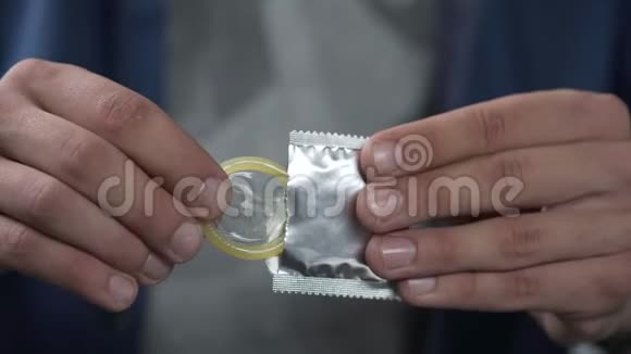 男人把避孕套从包装上拿出来并把它展示给相机性和医疗保健视频的预览图