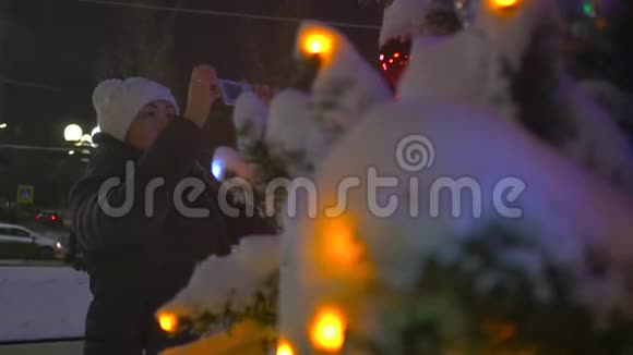 一个女孩正在公园的圣诞装饰背景上拍照视频的预览图
