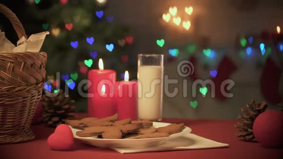 一杯牛奶和姜饼干放在桌子上圣诞树上闪烁着灯光视频的预览图