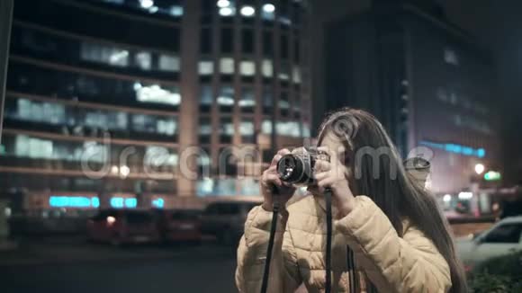 一位女摄影师为一个夜城的建筑拍照视频的预览图