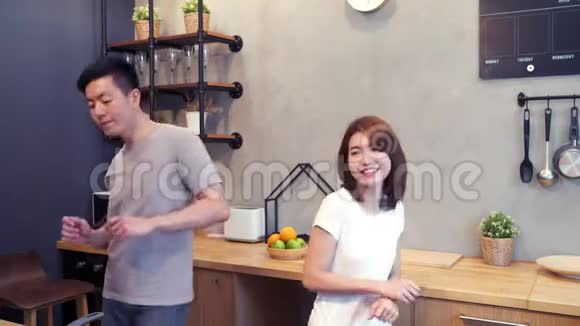 美丽快乐的亚洲夫妇正在家里的厨房里跳舞年轻的亚洲夫妇在听音乐时有浪漫的时光视频的预览图