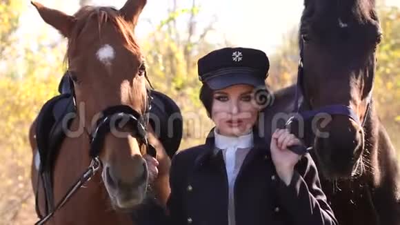 在秋日的阳光下一个女孩牵着两匹漂亮的马在缰绳后面视频的预览图