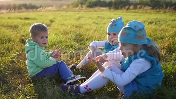 孩子们坐在公园的草坪上笑着笑孩子们露天度假视频的预览图
