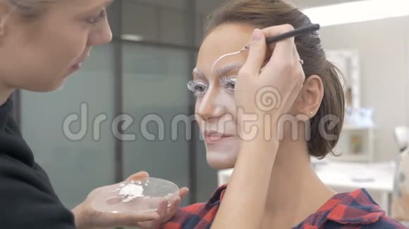 一位专业的化妆师在模特的脸上画身体艺术为选美比赛做准备视频的预览图