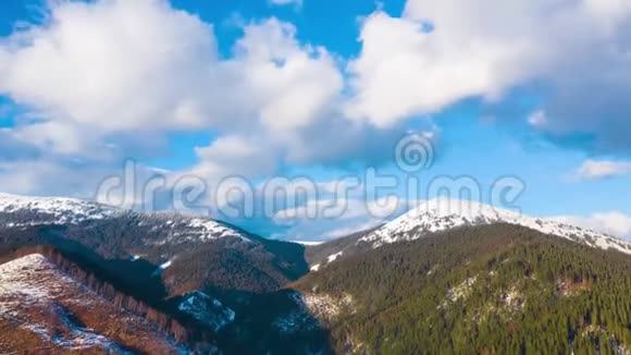 蓝天上的云层过度消散覆盖了高山雪山和针叶林的惊人景观视频的预览图