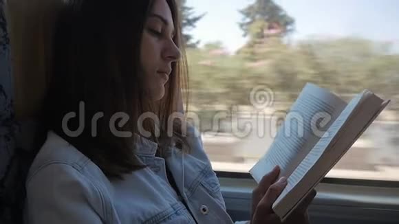 年轻女子乘公共汽车和看书女孩在车窗前的车里旅行视频的预览图