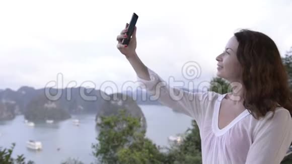 年轻女子在山顶自拍有大海和岛屿的背景视频的预览图