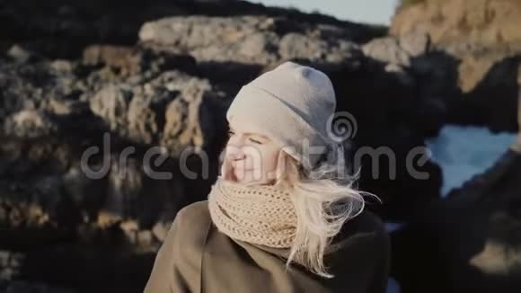年轻美丽的女人站在山旁环顾四周在阳光明媚的日子里头发在风中飘扬视频的预览图