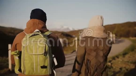 后景的旅行年轻夫妇走在大自然山谷阳光明媚的一天男人和女人在冰岛徒步旅行视频的预览图