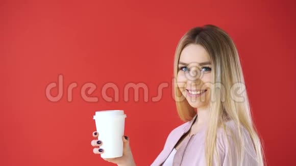 微笑放松的年轻女子和玻璃站着喝着咖啡拿起红墙背景视频的预览图