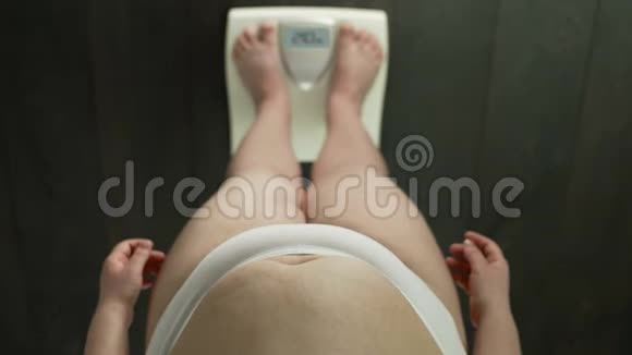肥胖的女人站在浴室秤上检查体重焦虑俯视视频的预览图