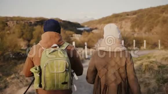 年轻夫妇的背面有一个浪漫的自然约会在山区山谷徒步旅行的男女视频的预览图
