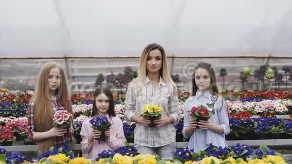四个女孩微笑着把花盆和照相机同步伸展的肖像视频的预览图