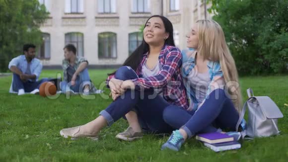 最好的朋友坐在大学附近的草坪上聊天支持和友谊视频的预览图