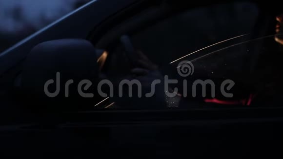 一个年轻的女人晚上坐在汽车的方向盘上视频的预览图