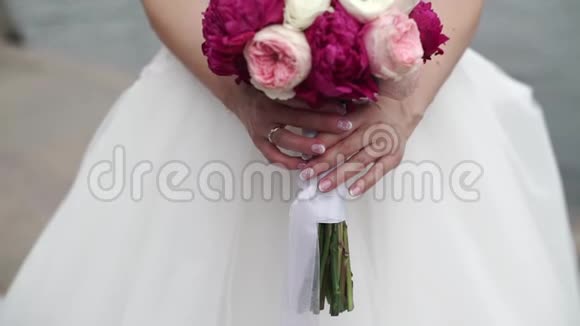 新娘捧着一束白色粉红色和红色的玫瑰摇摆的丝带户外活动缓慢视频的预览图
