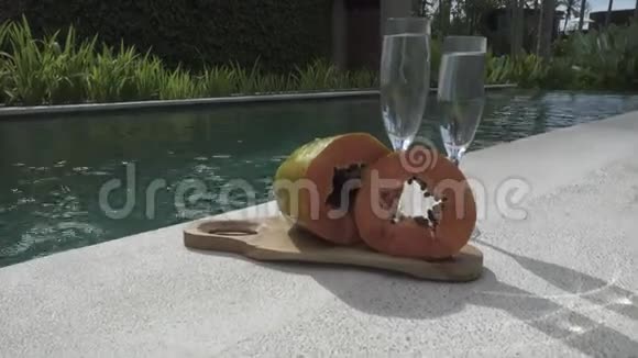 这位留着长发的年轻苗条女子在游泳池休息在热带度假胜地喝椰子鸡尾酒视频的预览图