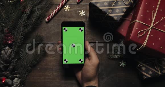 男性手拿着绿色屏幕的黑色智能手机铬钥匙上景垂直位置圣诞新年视频的预览图