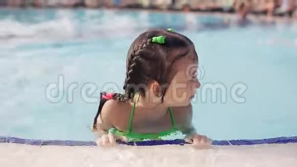 小女孩在游泳池里玩第一次学会游泳在海滩度假胜地度过暑假视频的预览图