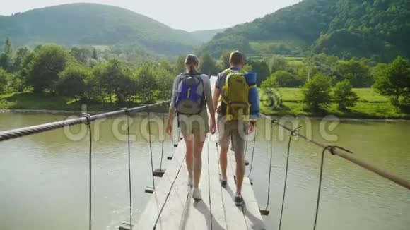 几个游客小心翼翼地走在一座不稳定的桥上越过一条山河后景稳定射击视频的预览图