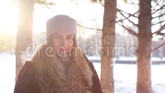 一个年轻的女孩在风雪和阳光的映衬下用手吹着一堆雪视频的预览图