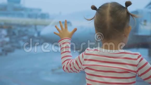 小女孩看着窗外的飞机后面视频的预览图