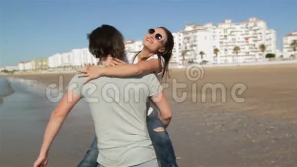 年轻的滑稽夫妇戴着太阳镜在海滩上骑着小猪朋友在一起玩得开心海在背景上视频的预览图