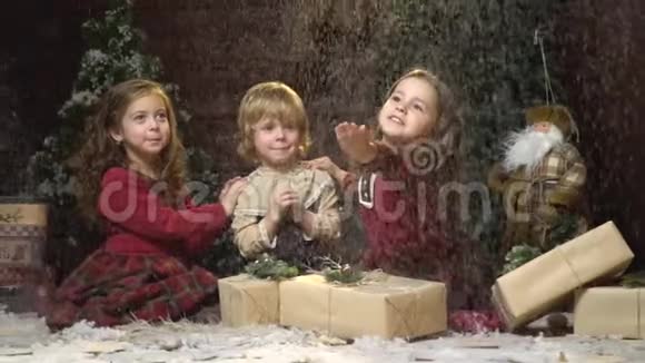 一个害羞的男孩坐在两个女孩之间穿着正在下雪的衣服一个有圣诞装饰的房间慢动作视频的预览图