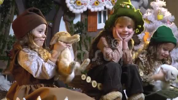 两个女孩在玩毛茸茸的兔子男孩微笑着看着它们等待圣诞节慢动作视频的预览图