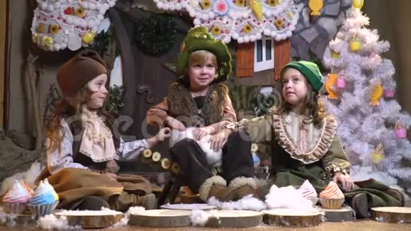 穿着老式圣诞服装的可爱的孩子们正和一只白兔坐在一起背景是视频的预览图