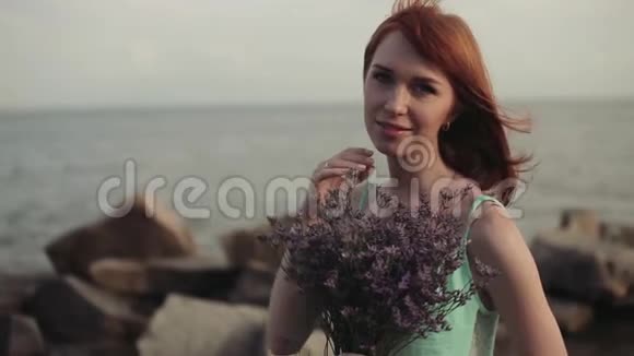 美丽的姑娘手里拿着鲜花摆在海边视频的预览图