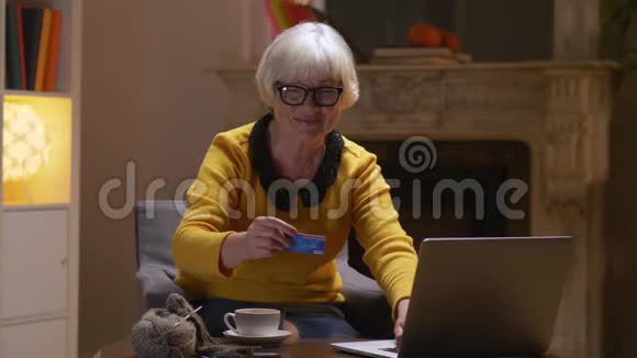 退休妇女使用信用卡进行网上家庭购物支付视频的预览图