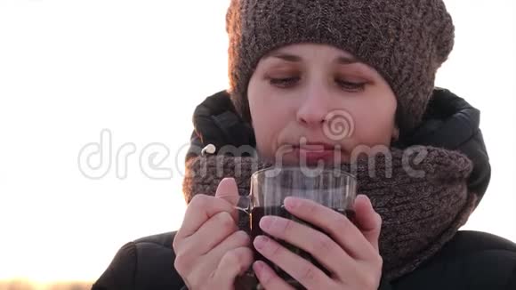 美丽的冷冻女孩在露天喝透明玻璃茶视频的预览图