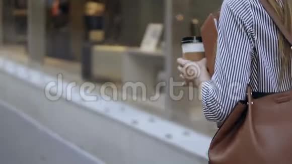 年轻时尚的女商人拿着文件和咖啡杯在街上走来走去用智能手机聊天视频的预览图