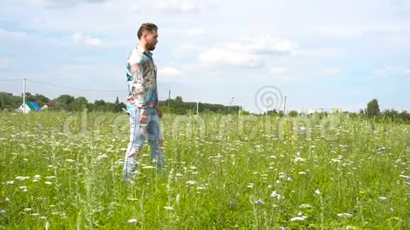 一个穿破牛仔裤的帅哥独自在草地上走来走去视频的预览图