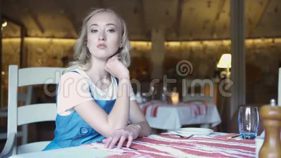 一个年轻的金发女人坐在家里厨房的肖像艺术年轻漂亮的金发女郎坐在厨房里视频的预览图