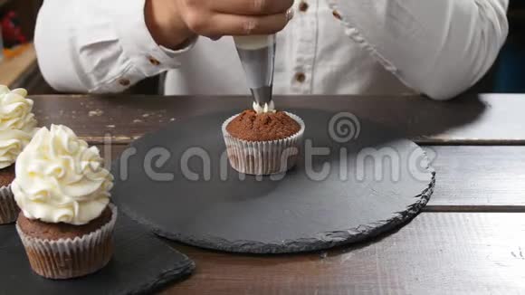 面包师用奶油装饰美味的纸杯蛋糕食物及糖果概念视频的预览图