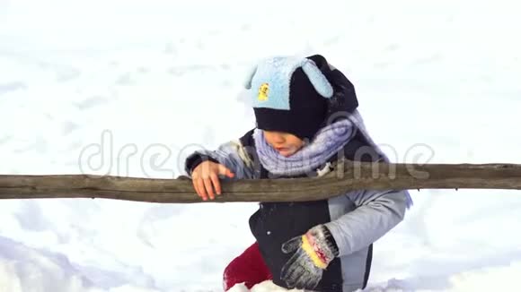 一个快乐的小男孩正在雪地里玩耍他的手套掉进了雪里视频的预览图