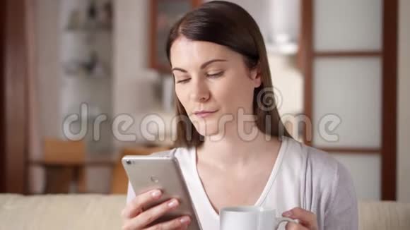 微笑的职业妇女在家里用手机喝咖啡家庭办公概念视频的预览图