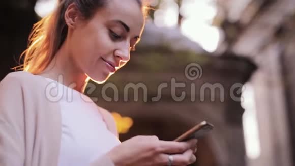 有魅力的年轻女性在街上行走时使用手机视频的预览图
