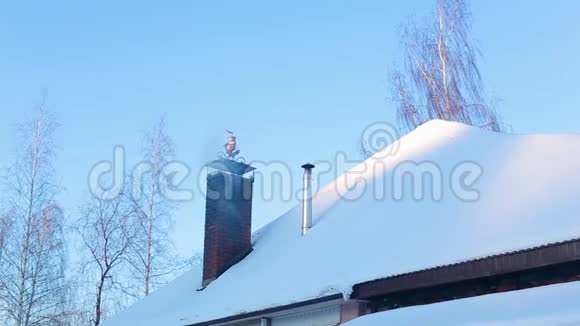 有烟囱有烟的房子的部分白雪覆盖的屋顶视频的预览图