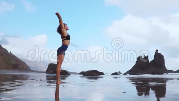 美丽的运动女郎穿着运动服在海洋低潮后做运动来热身和调整肌肉这就是视频的预览图