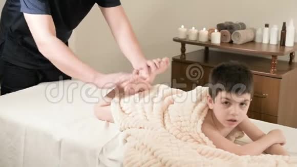 一位男性理疗师按摩师为躺在按摩床上的一个小男孩做了一次轻松的按摩和伸展视频的预览图