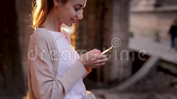 有魅力的年轻女性在街上行走时使用手机视频的预览图