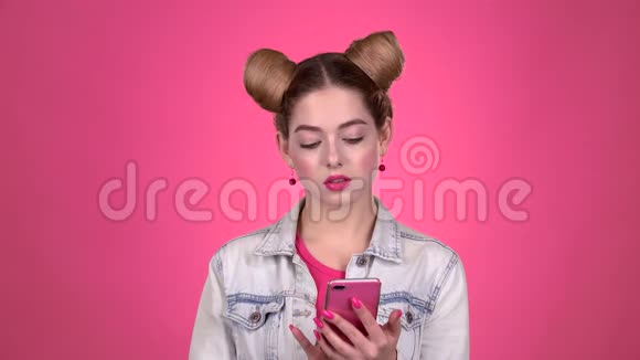 青少年在智能手机上竖起大拇指粉色背景慢动作视频的预览图