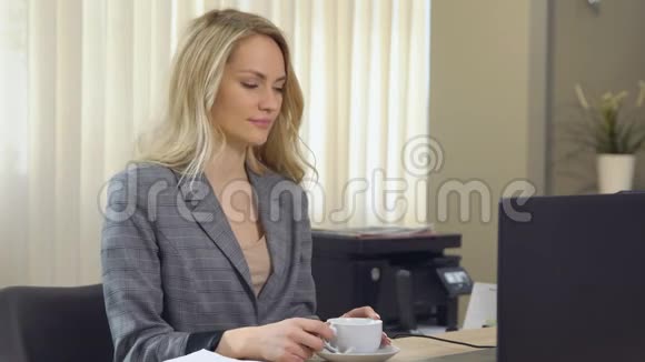 穿西装的漂亮女商人在工作场所与杯咖啡一起工作视频的预览图