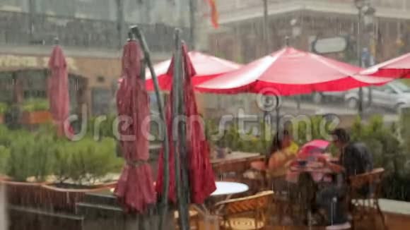 一对夫妇在咖啡馆露台上吃午饭在雨中浪漫约会恋爱视频的预览图