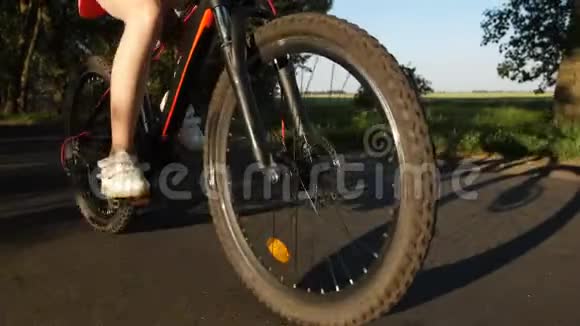 青少年腿和自行车轮在道路上的特写视频的预览图