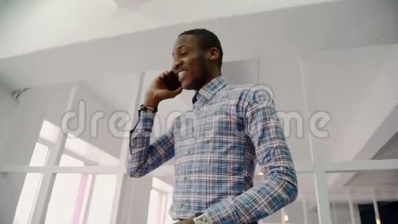 一幅美国黑人高级设计师在明亮的工作室走廊上打电话的画像视频的预览图