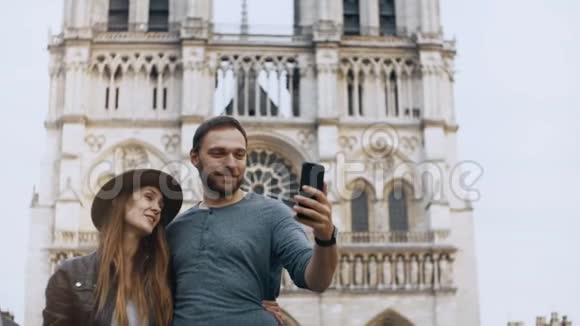年轻的幸福夫妇在法国巴黎圣母院附近的智能手机上自拍欣赏美丽的景色视频的预览图